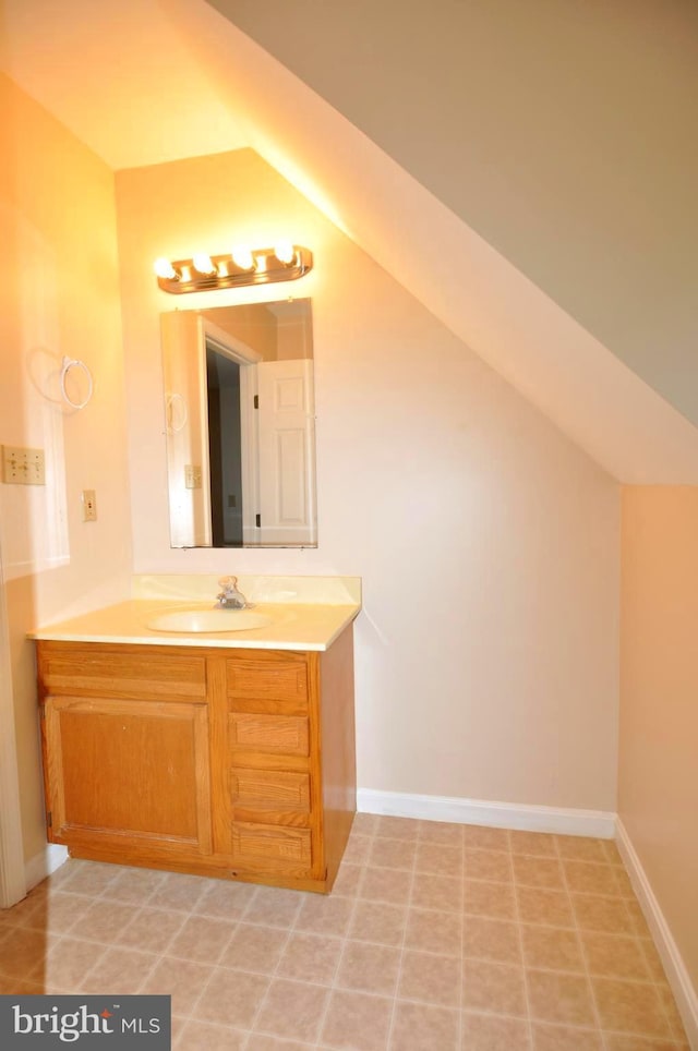 bathroom with vanity, baseboards, and lofted ceiling