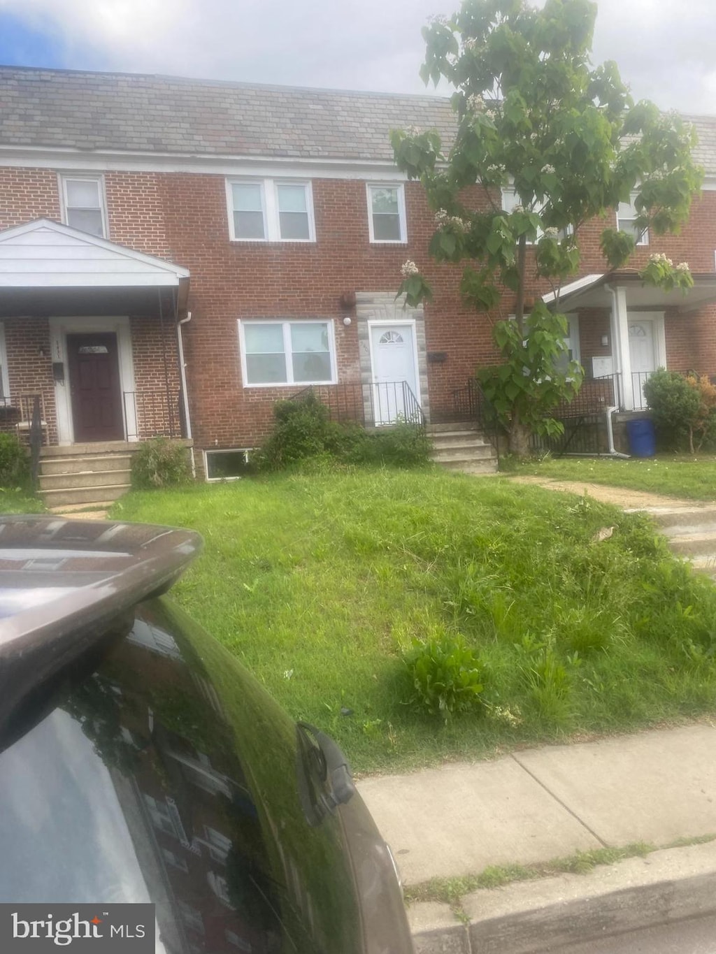 view of property featuring brick siding and a front lawn