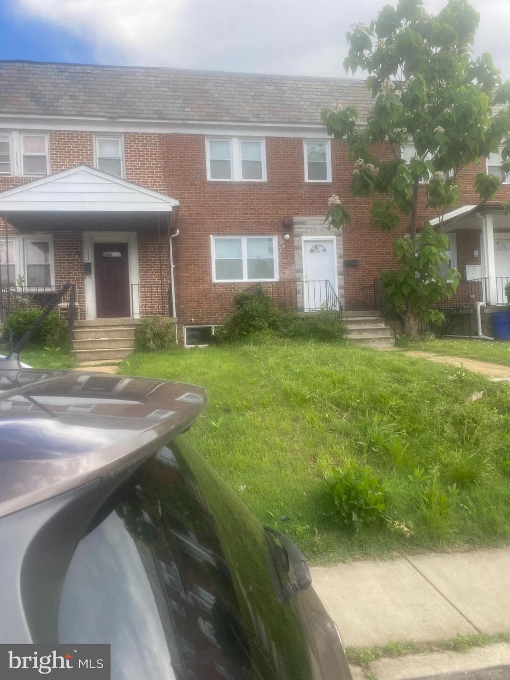 townhome / multi-family property with brick siding and a front lawn