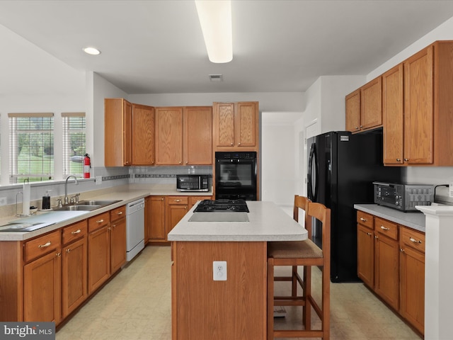 5204 Spanish Dollar Ct, Woodbridge, VA 22193 - kitchen featuring a sink, black appliances, light floors, a center island, and a kitchen bar