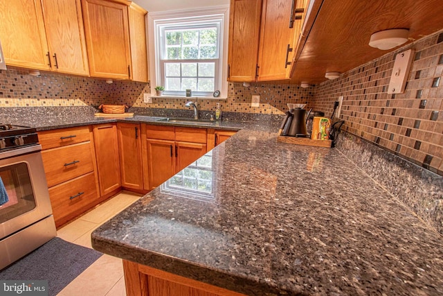 14365 Salsbury Ct, Woodbridge, VA 22193 - kitchen with stainless steel range with gas cooktop, decorative backsplash, a sink, light tile patterned floors, and dark stone countertops