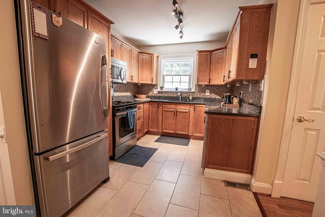 14365 Salsbury Ct, Woodbridge, VA 22193 - kitchen featuring stainless steel appliances, tasteful backsplash, light tile patterned floors, and brown cabinets