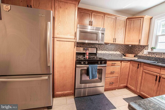 14365 Salsbury Ct, Woodbridge, VA 22193 - kitchen featuring stainless steel appliances, light tile patterned floors, tasteful backsplash, and dark stone counters