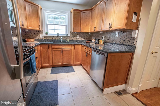 14365 Salsbury Ct, Woodbridge, VA 22193 - kitchen with stainless steel appliances, a sink, backsplash, dark stone countertops, and baseboards