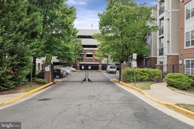 12958 Centre Park Cir Unit 219, Herndon, VA 20171 - view of asphalt road with a gate, curbs, a gated entry, and traffic signs