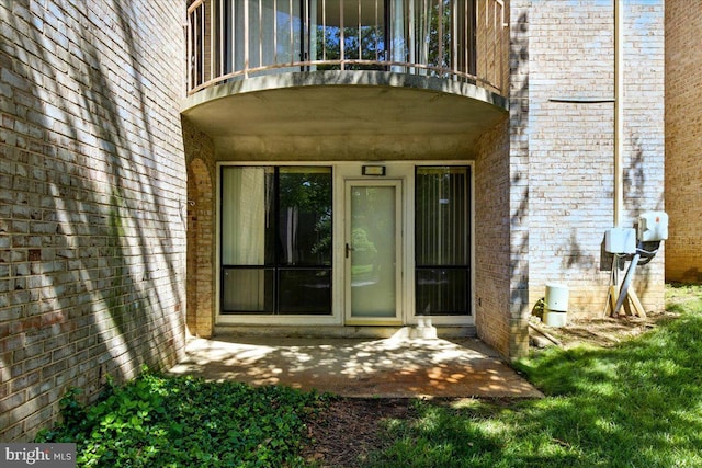 entrance to property featuring a balcony and brick siding