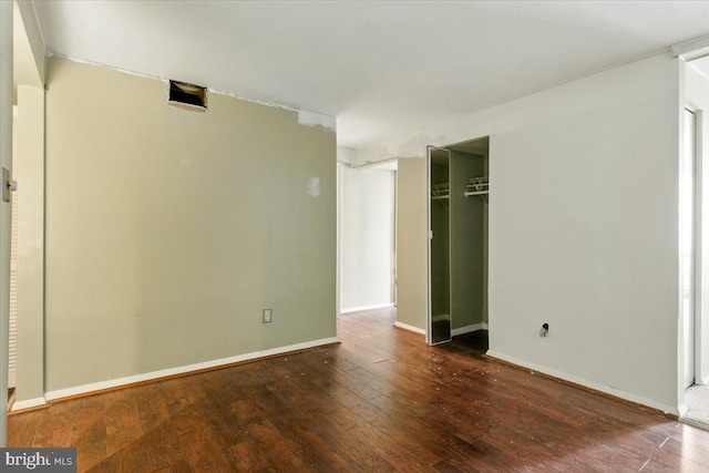 unfurnished bedroom with hardwood / wood-style floors, baseboards, and a closet