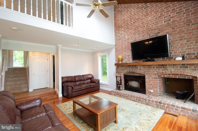 5470 Moose Lodge Rd, Cambridge, MD 21613 - living room with a brick fireplace, wood finished floors, a high ceiling, ceiling fan, and stairs