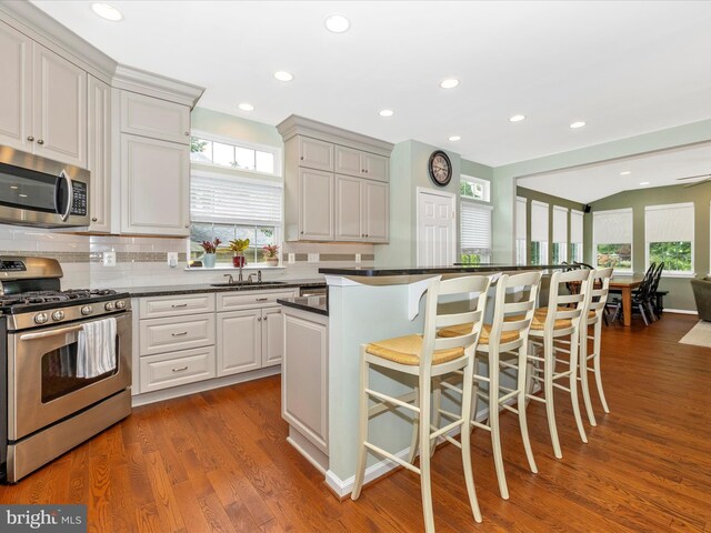 6470 Saddlebrook Ln, Frederick, MD 21701 - kitchen featuring stainless steel appliances, a sink, dark countertops, a kitchen bar, and tasteful backsplash