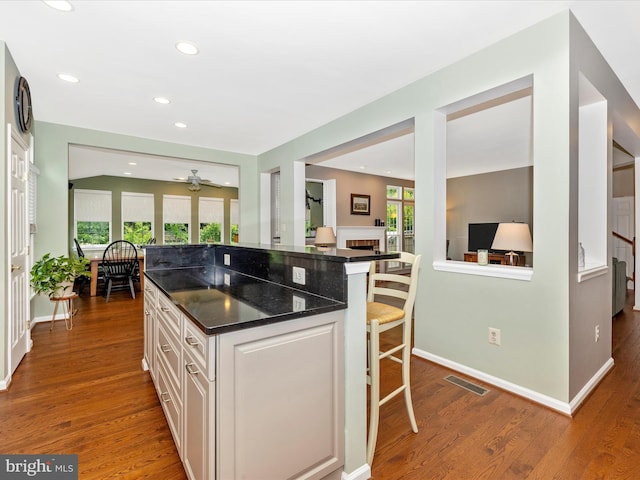 6470 Saddlebrook Ln, Frederick, MD 21701 - kitchen with a breakfast bar area, dark wood finished floors, white cabinets, a fireplace, and recessed lighting