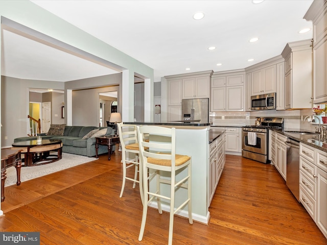 6470 Saddlebrook Ln, Frederick, MD 21701 - kitchen featuring stainless steel appliances, a sink, a breakfast bar area, decorative backsplash, and wood finished floors