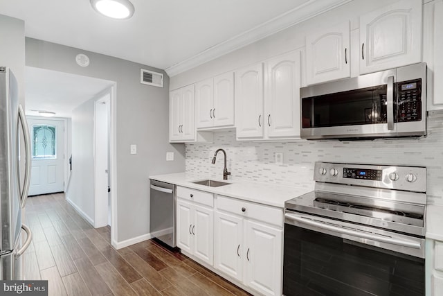 kitchen featuring stainless steel appliances, a sink, light countertops, white cabinetry, and crown molding