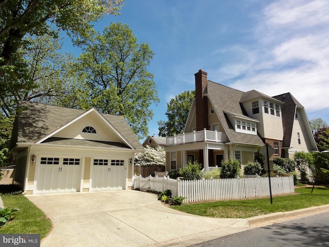 view of front of property with a balcony, fence, roof with shingles, a chimney, and concrete driveway
