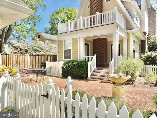 doorway to property with a balcony, fence, and covered porch