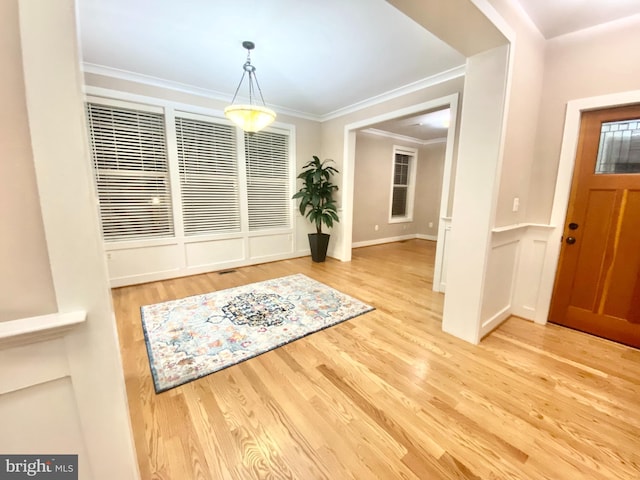 entryway with wood finished floors and crown molding