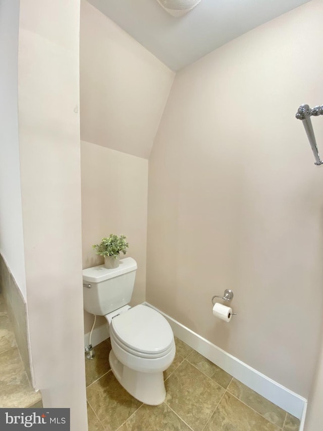 bathroom featuring toilet, vaulted ceiling, baseboards, and tile patterned floors