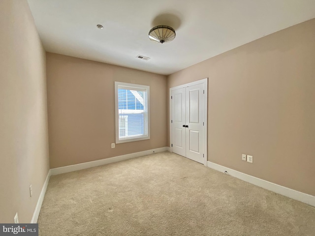 unfurnished bedroom with light carpet, baseboards, and a closet