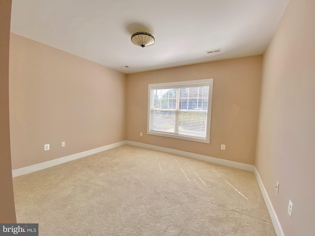 empty room featuring light carpet and baseboards