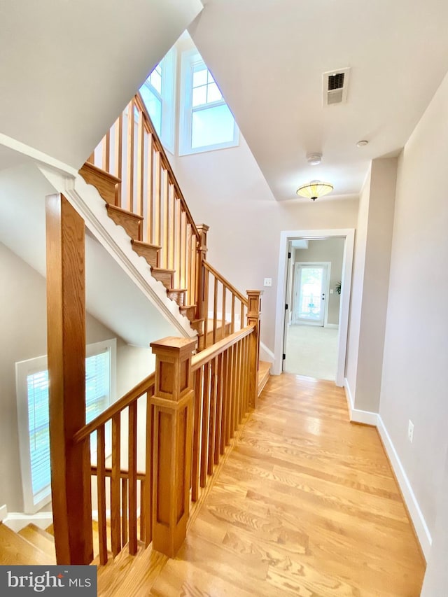 stairs with healthy amount of natural light, wood finished floors, and baseboards