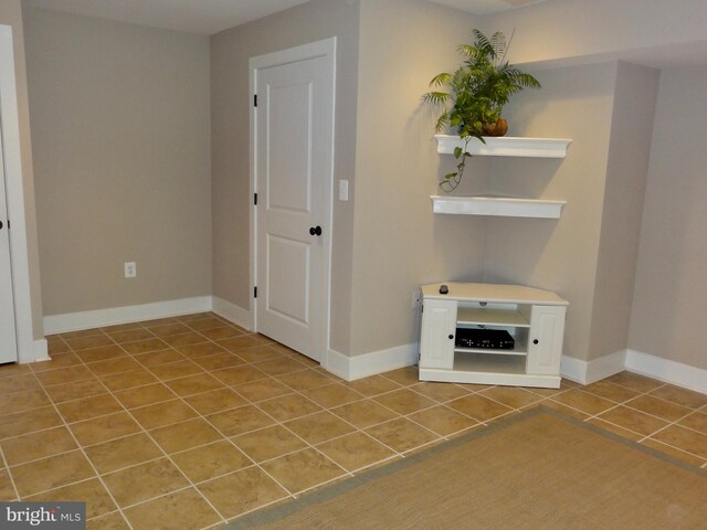 spare room with tile patterned flooring and baseboards