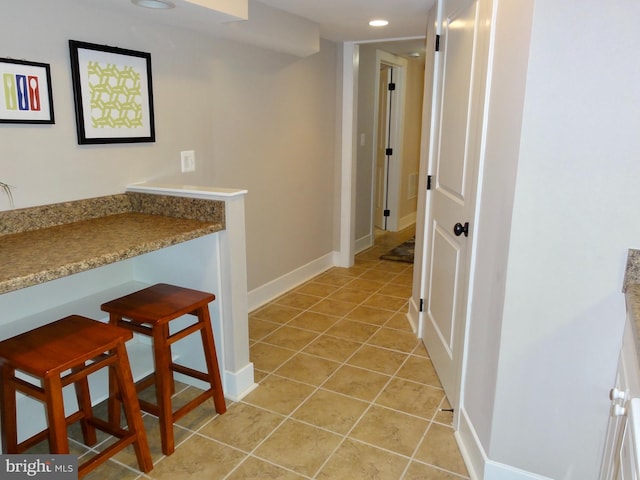 hallway featuring light tile patterned flooring, baseboards, and recessed lighting