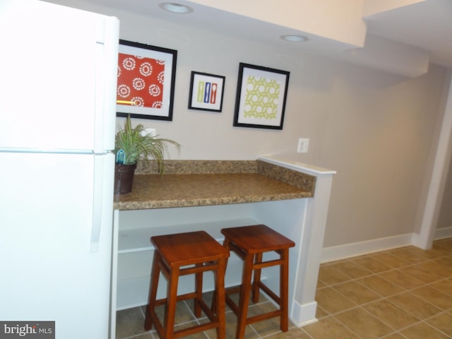 bar with freestanding refrigerator, tile patterned floors, baseboards, and recessed lighting