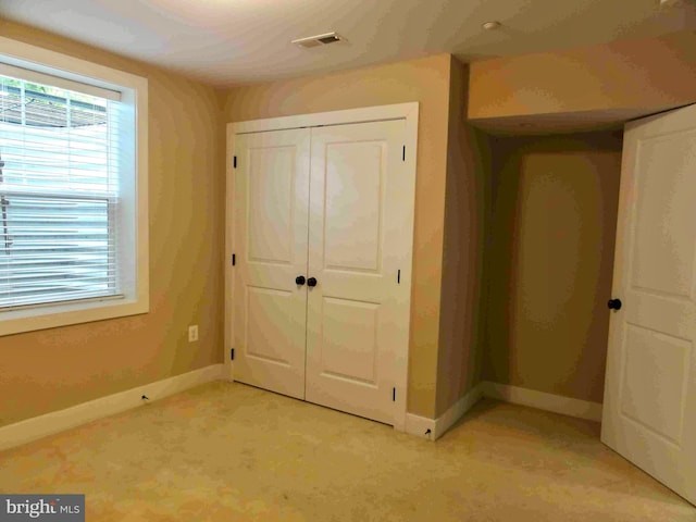 unfurnished bedroom featuring a closet, baseboards, and light colored carpet