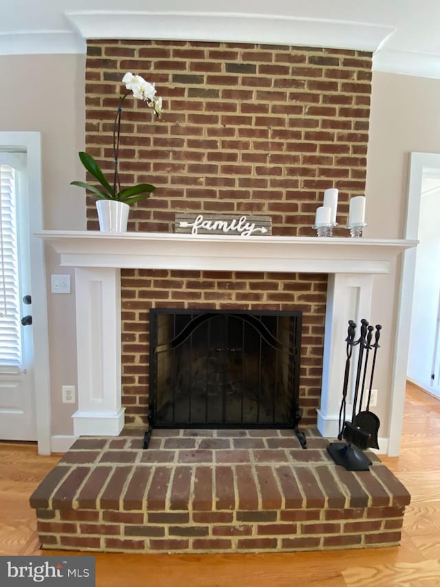 detailed view of a fireplace, wood finished floors, crown molding, and baseboards