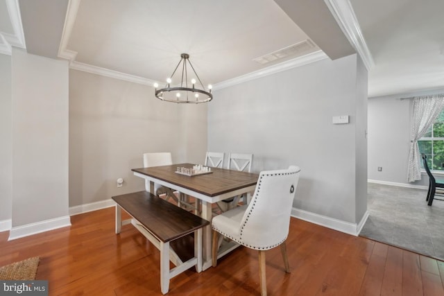 dining space featuring hardwood / wood-style flooring, a chandelier, crown molding, and baseboards