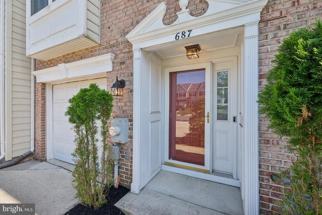 entrance to property featuring brick siding and a garage