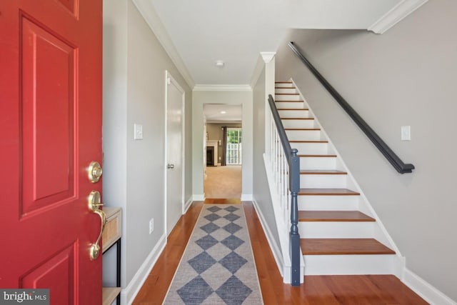 entrance foyer featuring stairs, wood finished floors, crown molding, and baseboards