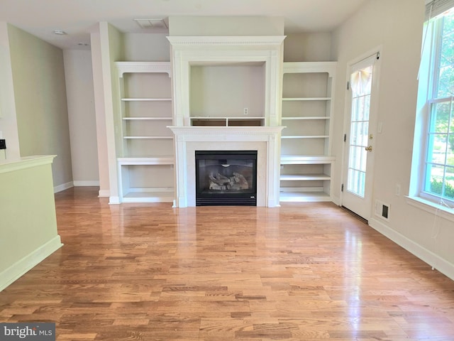10 Honeyflower, Bordentown, NJ 08620 - unfurnished living room featuring wood finished floors, baseboards, built in shelves, and a glass covered fireplace