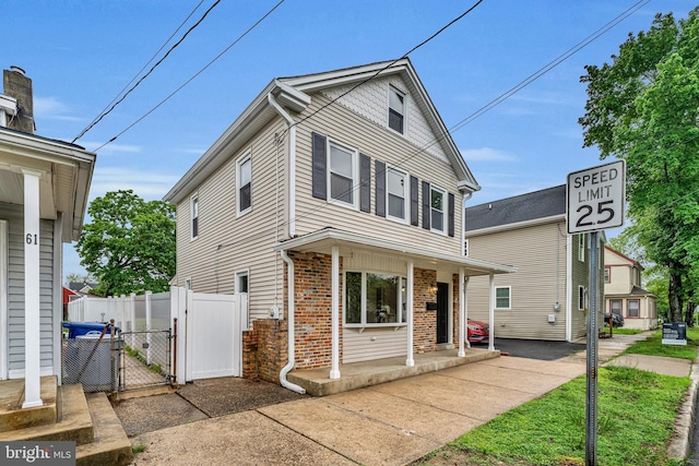 59 Jarvis St, Pemberton, NJ 08068 - view of front facade with a gate, brick siding, covered porch, and fence