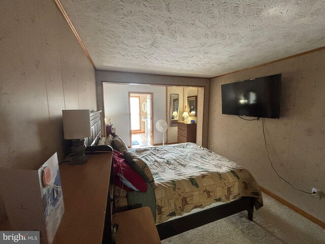 carpeted bedroom with a textured ceiling, wood walls, and baseboards