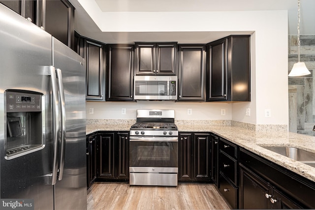 5831 Rochefort St, Ijamsville, MD 21754 - kitchen with appliances with stainless steel finishes, light stone countertops, dark cabinets, and light wood-type flooring