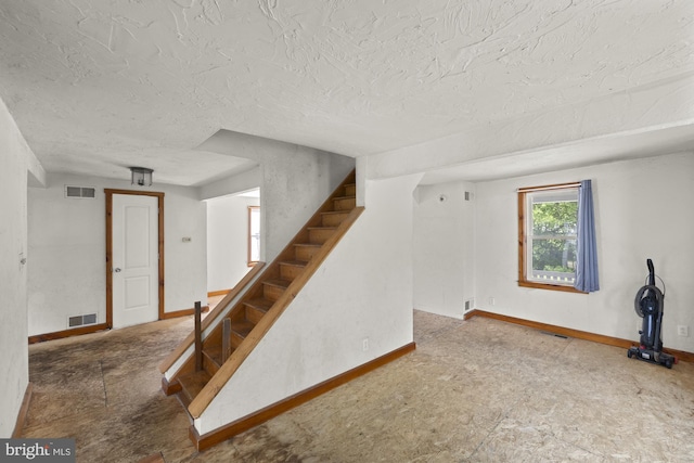 below grade area with stairs, baseboards, and a textured ceiling