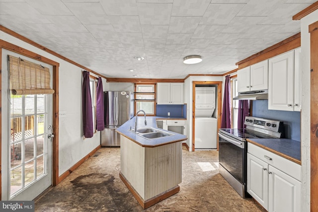 kitchen with appliances with stainless steel finishes, stacked washing machine and dryer, a sink, ornamental molding, and white cabinetry