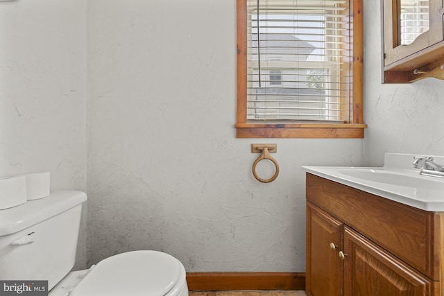 half bath featuring healthy amount of natural light, vanity, and toilet
