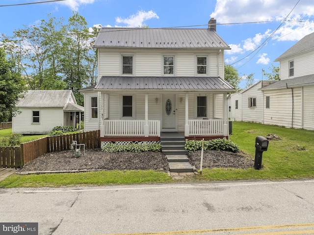 view of front of home with covered porch, metal roof, a front yard, and a chimney
