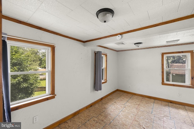 empty room featuring healthy amount of natural light, baseboards, a smoke detector, and crown molding