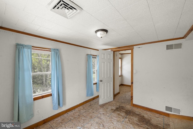 empty room featuring crown molding and baseboards