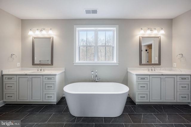 full bathroom with two vanities, a soaking tub, and baseboards