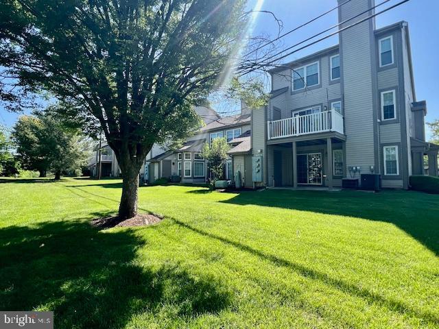 view of grassy yard with a balcony