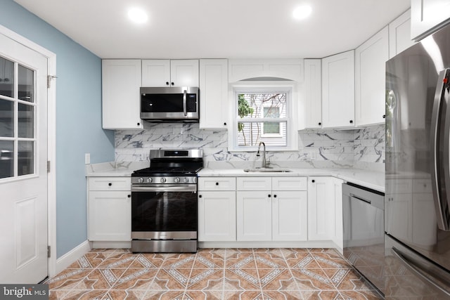 kitchen featuring stainless steel appliances, a sink, tasteful backsplash, white cabinetry, and recessed lighting