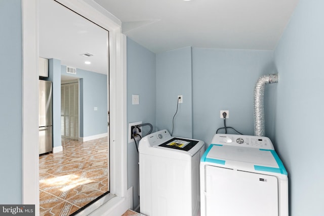clothes washing area with washer and dryer and light tile patterned floors