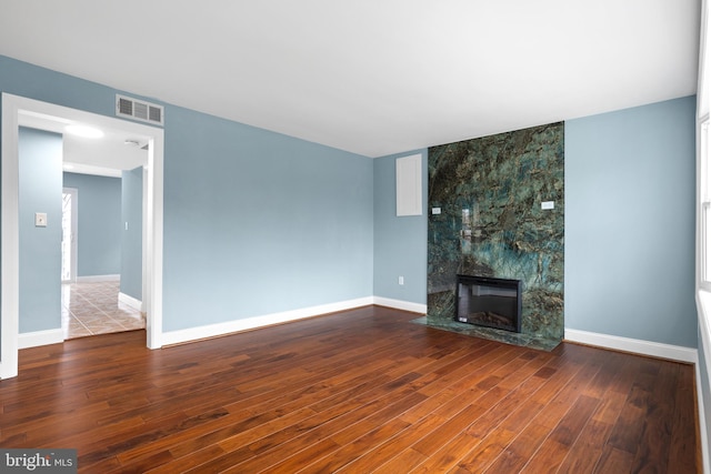 unfurnished living room with wood finished floors, a large fireplace, and baseboards