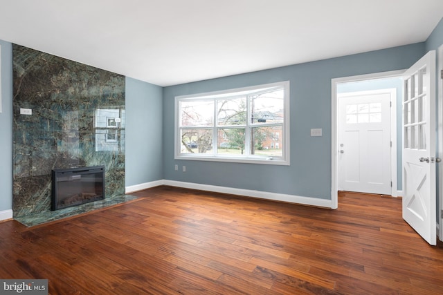 unfurnished living room with a premium fireplace, baseboards, and wood finished floors