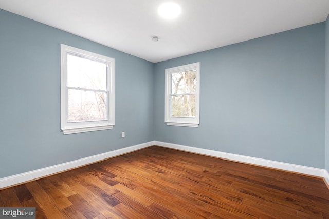 unfurnished room with baseboards and dark wood finished floors
