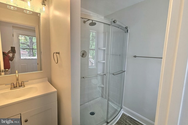 full bath featuring a stall shower, vanity, and baseboards