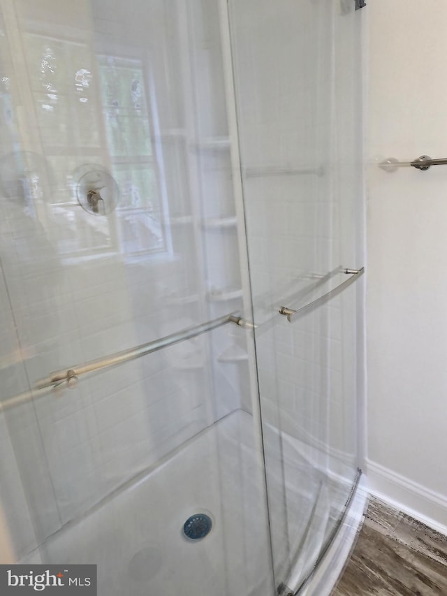 bathroom with a shower stall, baseboards, and wood finished floors
